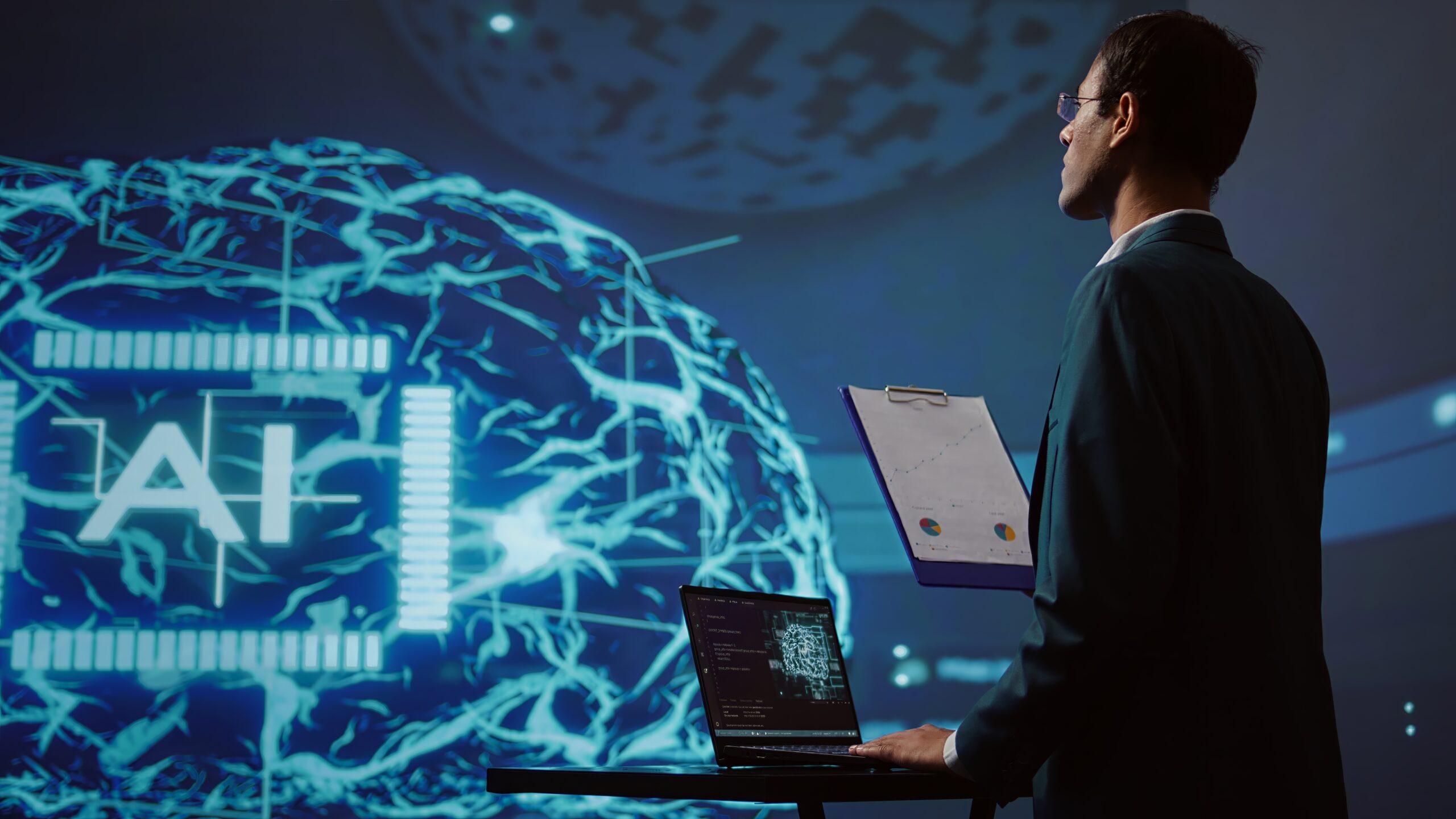 AI development team analyzing a holographic brain interface on a large screen, with a laptop displaying neural network code in the foreground.